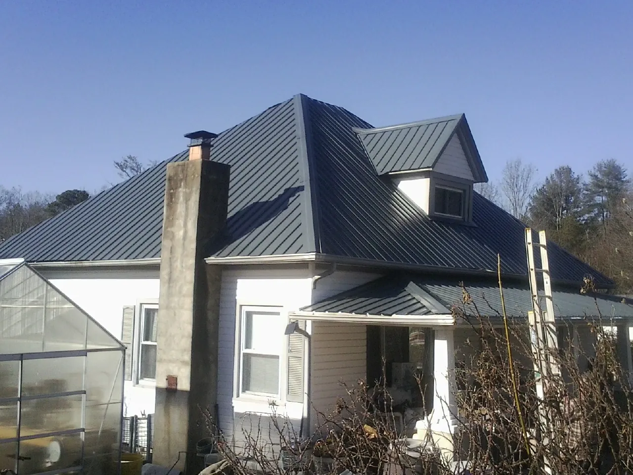 Dark blue standing seam metal roof on a white farmhouse with dormer — Slate & Tile Roof Repair by Roofing Brothers in South San Francisco
