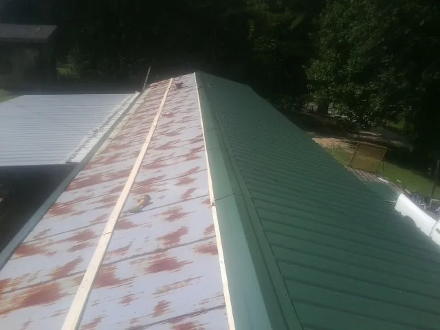 Old rusted panels beside newly installed green metal roofing — Wind Damage Roof Repair by Roofing Brothers in South San Francisco