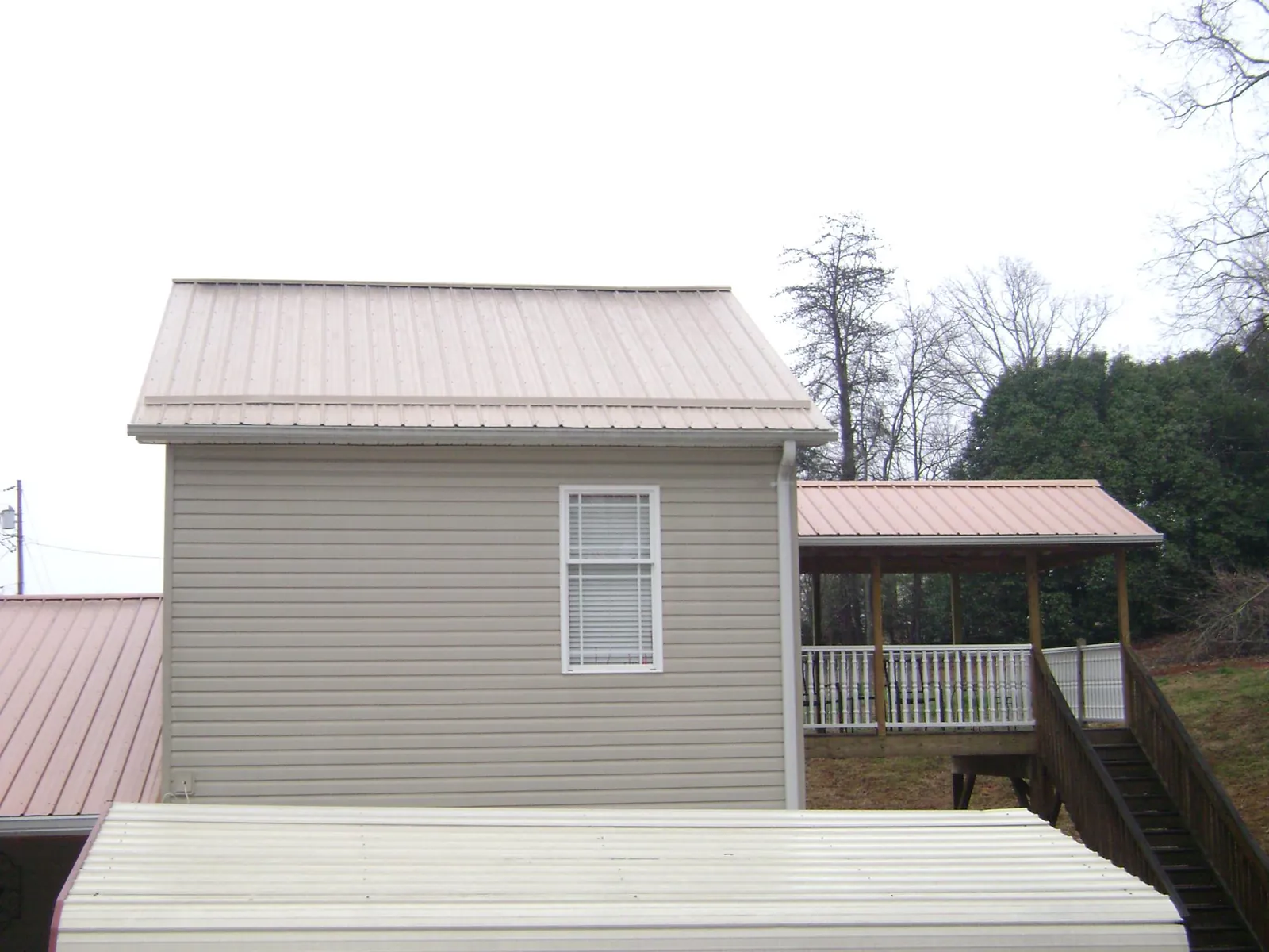 Tan metal roofs on a two story addition and attached porch, from a Roof Replacement job in South San Francisco