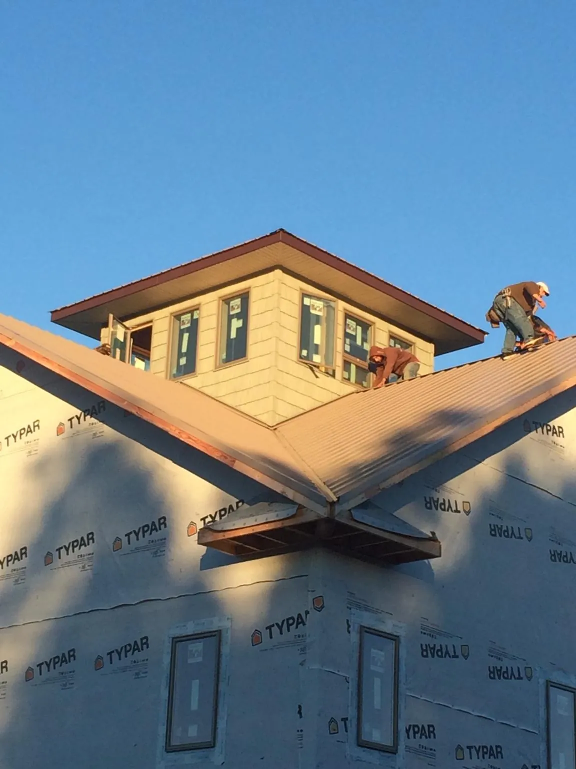 Roofers working around a rooftop cupola on a new metal roof at sunset — Roof Waterproofing in South San Francisco by Roofing Brothers